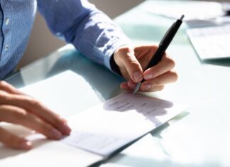 Comment remplir un chèque ? Homme qui remplit un chèque