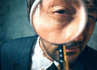 Comment retrouver une personne perdue de vue ? Homme avec une loupe